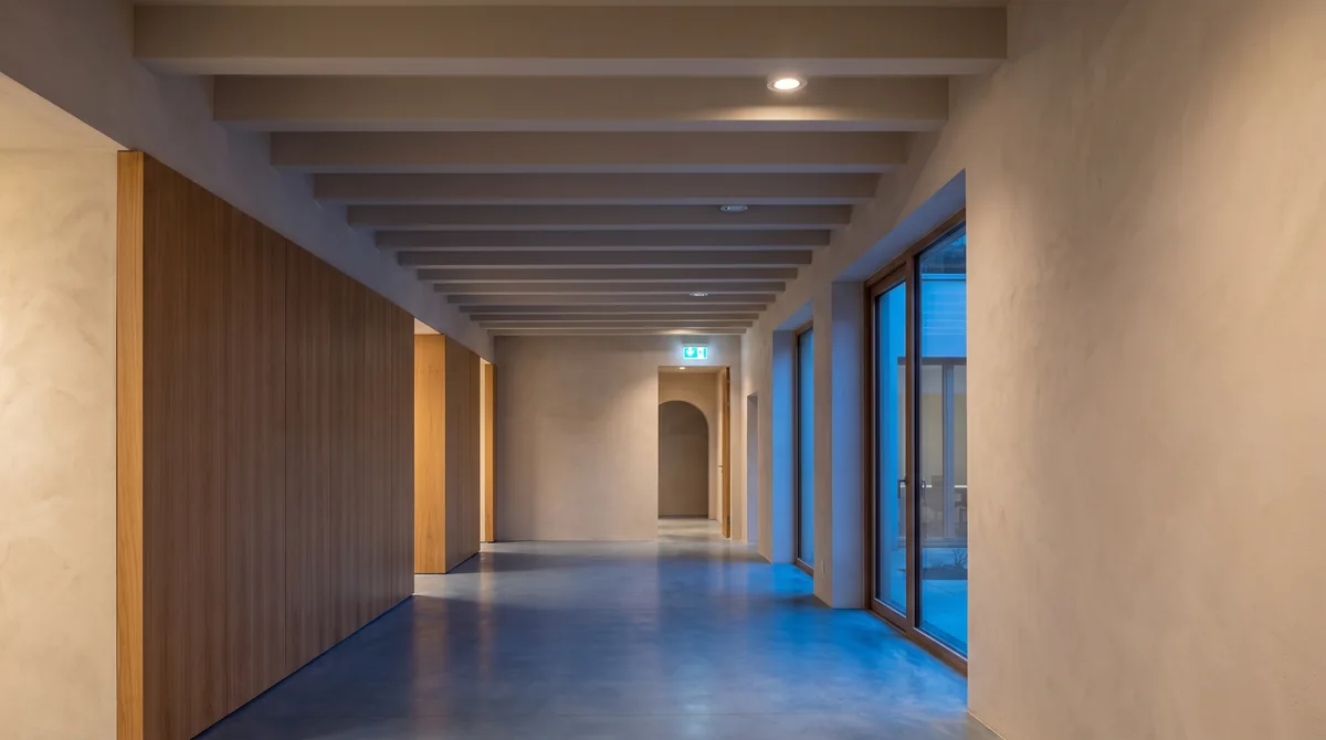 A warmly lit shared corridor with emergency exit lighting.